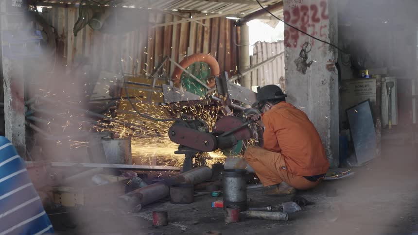A man welds equipment in a corrugated building