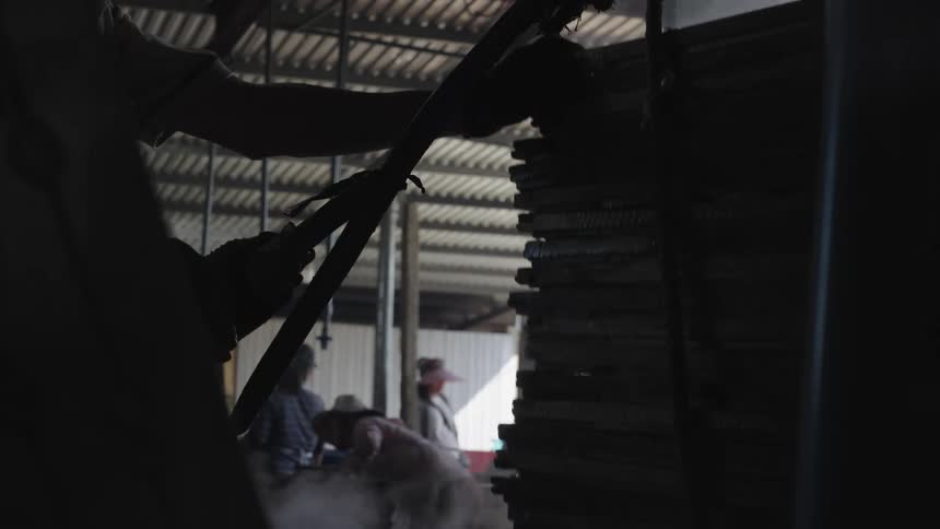 A worker pulls out a stack of steaming slabs from an oven in a fishery
