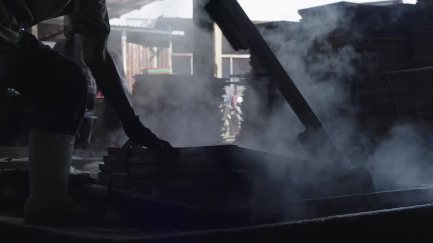 Person carrying out work in a metal basin with boiling water