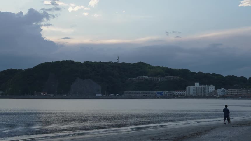 A serene beach with a person walking along the shoreline