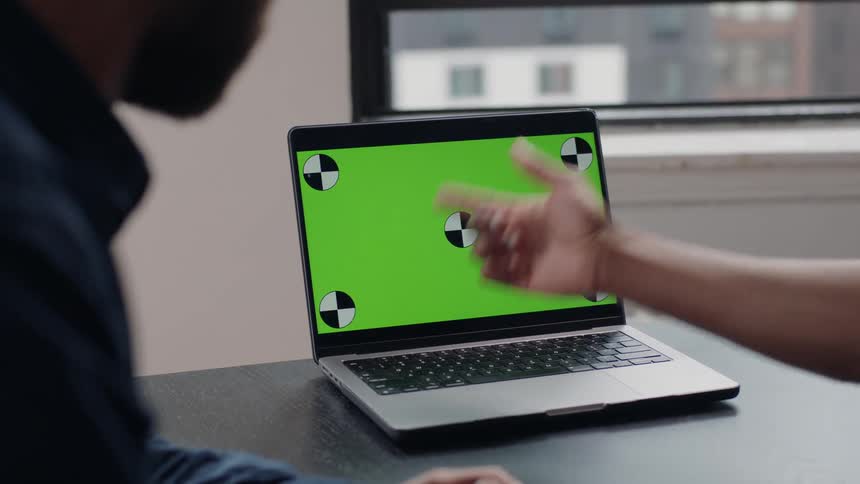 Laptop on top of an office table with two people around it
