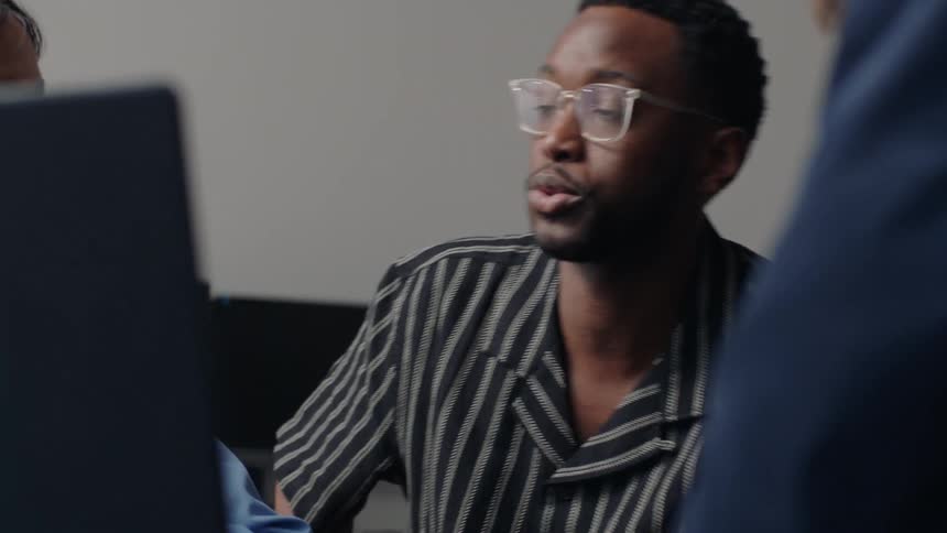 Two men in an office with a laptop talking