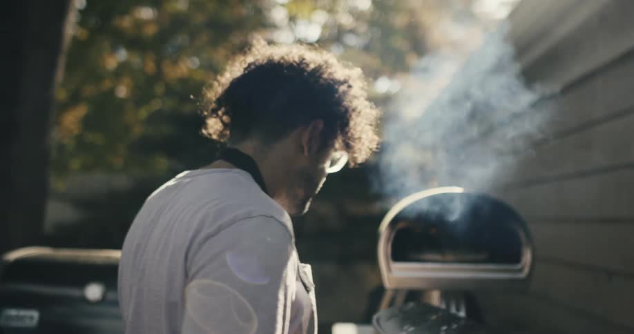A man cooking pizza outdoors in a pizza oven