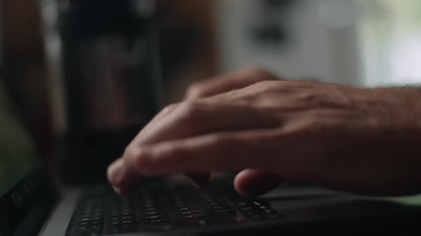 A man types on the keyboard of a laptop computer