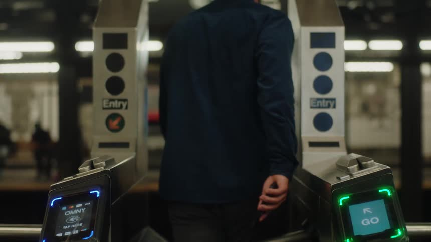 A man pays at a subway payment processor and then strolls through