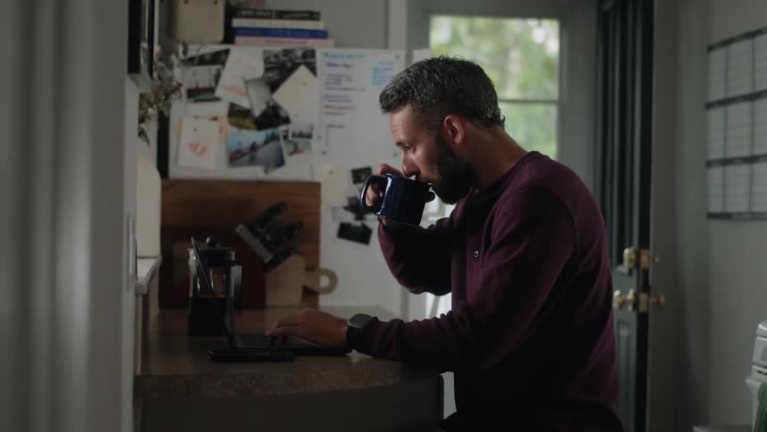 Man sitting working on a laptop and drinking a coffee