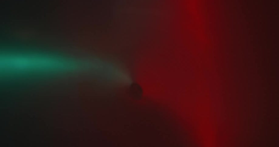 A dark blurry background with a gradient of green to red colors
