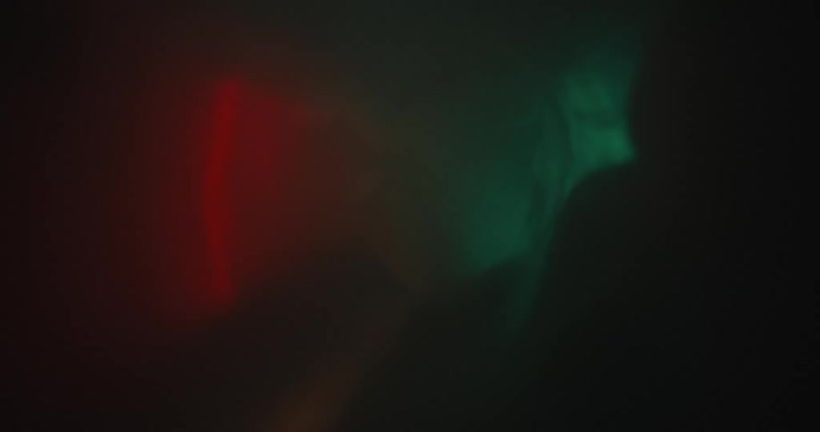 The interior of a semi translucent plastic tube with green and red lights reflecting on its walls filled with smoke