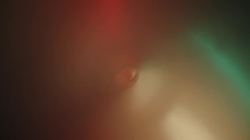 White whisps of smoke coming out of a dark blurry background with a gradient of green to red colors