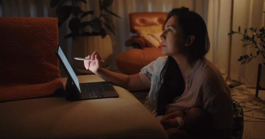 A woman reads something on a laptop and rubs her brow sadly