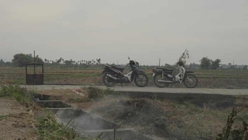 Smoke rises from the ground near two motorcycles