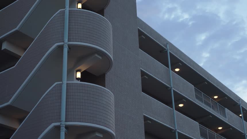 Part of a modern building with several curved balconies and external lighting
