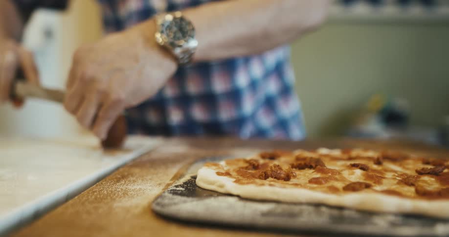Man finishing a baked pizza