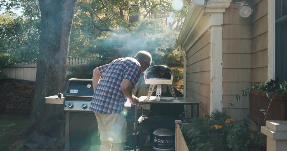Man preparing a pizza in an outdoor oven in the backyard of the house