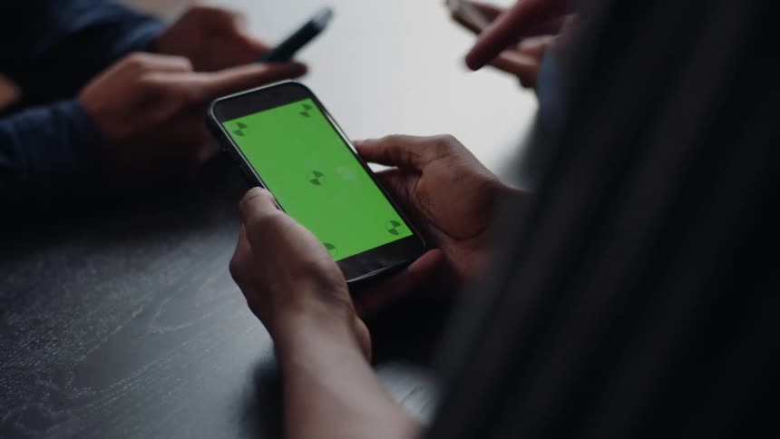 Three people at a business table using cell phones
