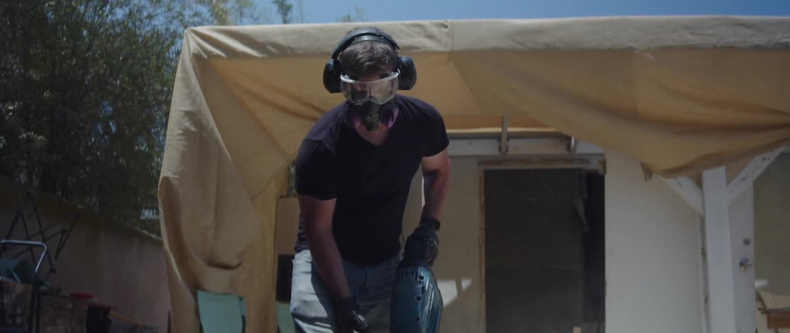 Man uses a jackhammer to demolish the brick patio floor in the yard