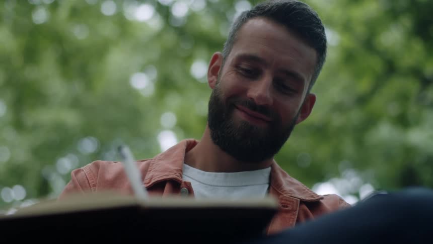 Portrait of a man sitting in a park writing