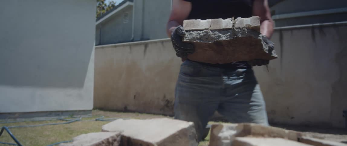 A worker piling up bricks on the backyard on a sunny day