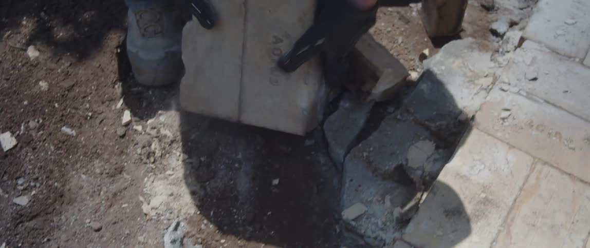 Pair of hands of a man in gloves removing concrete blocks