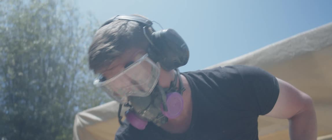 Concentrated man using a headset and protective mask handling a jackhammer