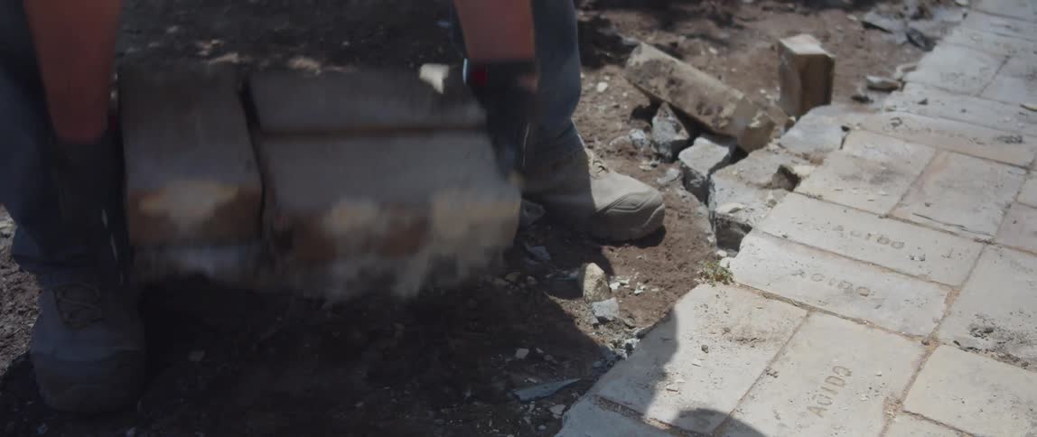 A construction worker lifts bricks and puts them on a cart