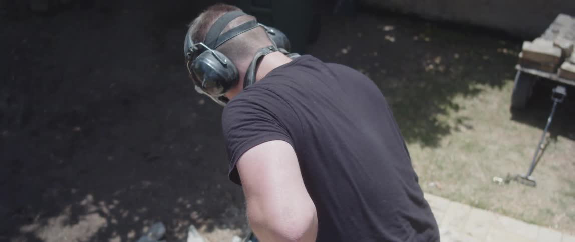 A worker in heavyduty boots operates a jackhammer breaking up a flagstone flooring