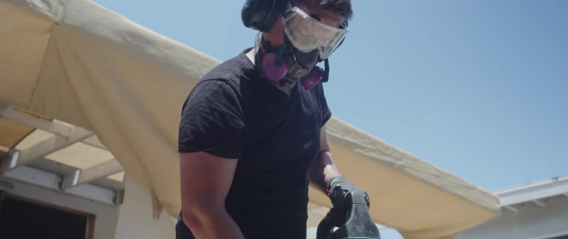 A worker in heavyduty boots operates a jackhammer breaking up concrete