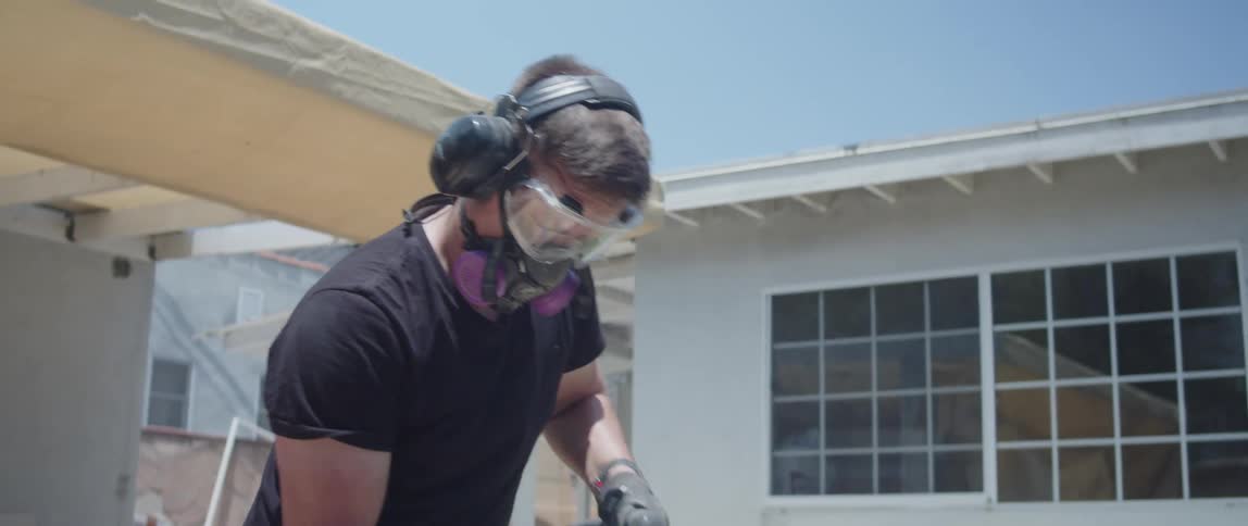 Man with protective mask using a jackhammer to break a concrete floor