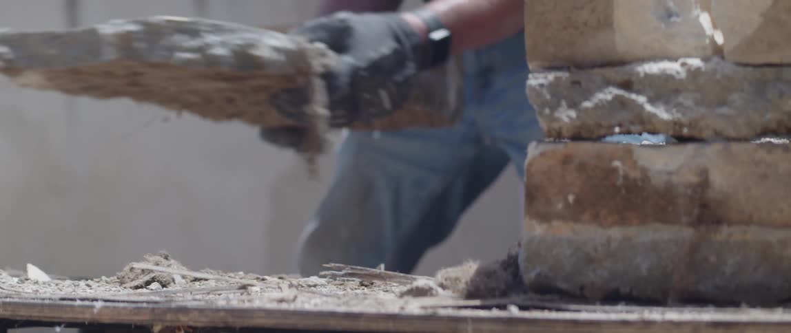 A construction worker puts a chunk of bricks on a wooden table