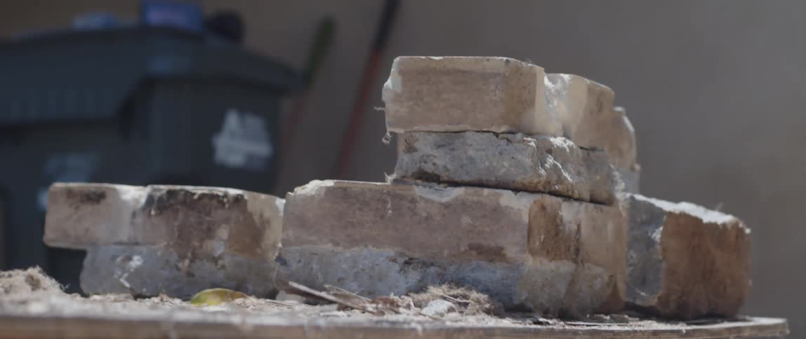 Hand with gloves picking up concrete stones and placing them on top of the other