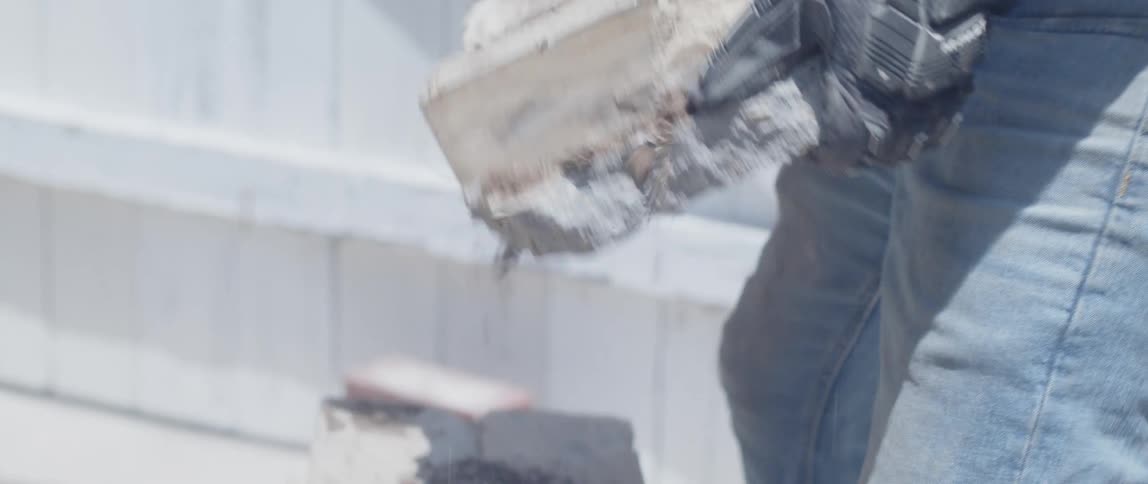 Hands with gloves picking up pieces of concrete and throwing