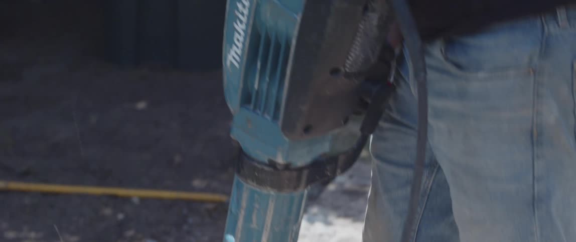 Man with glasses and protective mask working on removing a concrete floor with a jackhammer