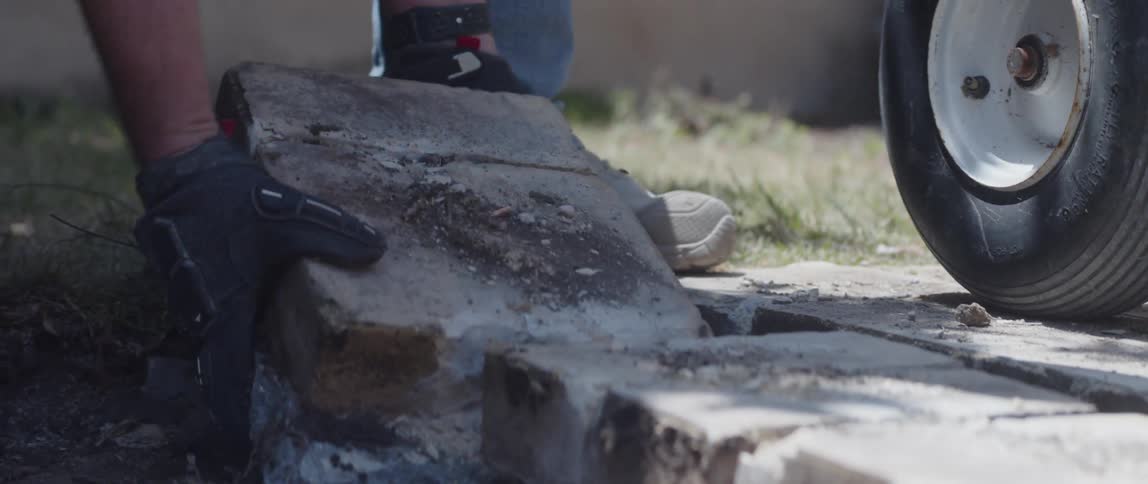 Pair of hands of a man with gloves removing concrete blocks and placing them on a table