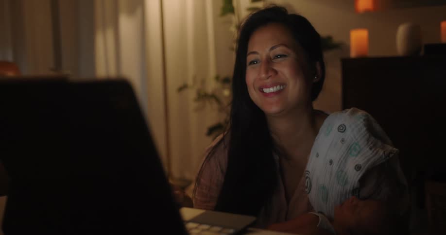 Woman sitting in living room laughs while watching laptop screen