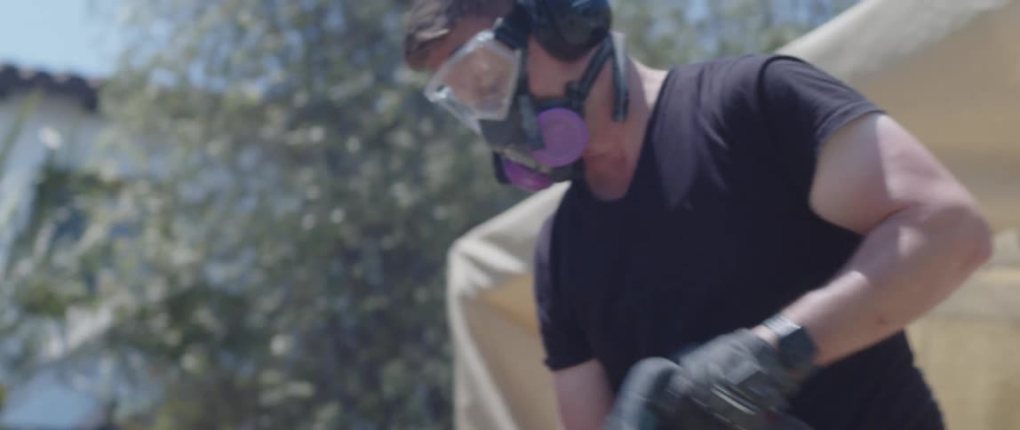Man with protective mask using a jackhammer to remove concrete blocks from a floor