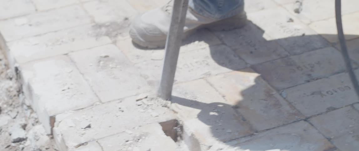 A man is breaking bricks with a jackhammer