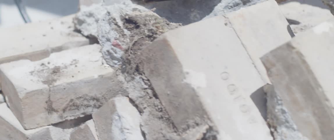 A man drags a cart full of bricks through the yard