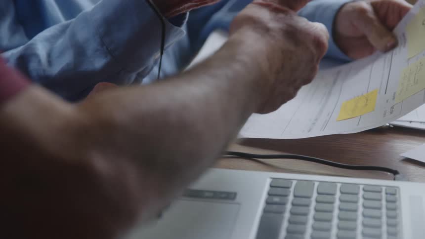 Coworkers discuss elements on a sheet of paper in an office