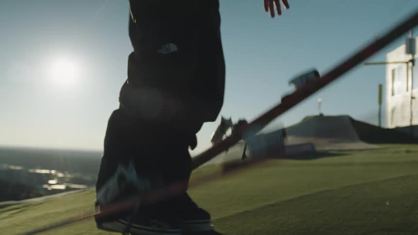A person drops two snowboards on a green grass ground