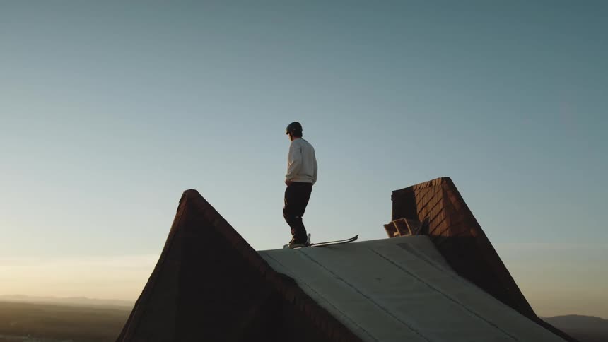 A skier standing at the top of a high jump ramp at sunrise