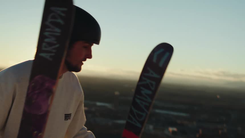 A man climbs up the mountain carrying skis