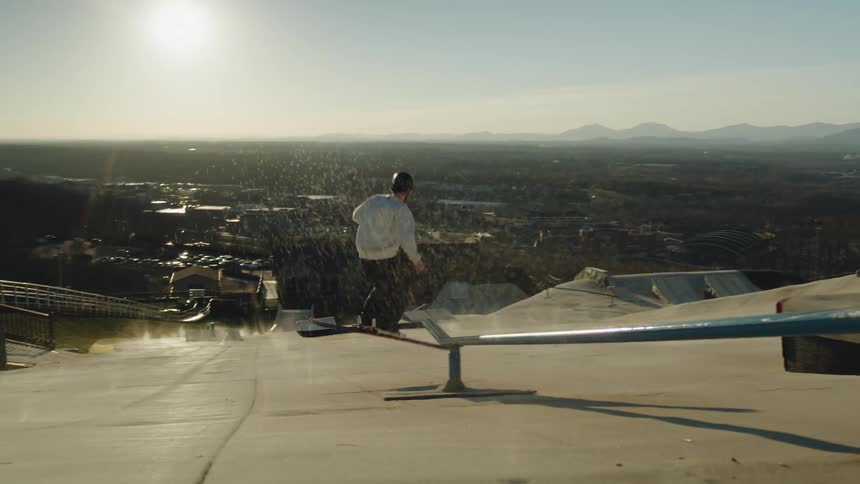 Man going down a metal ramp with ski equipment