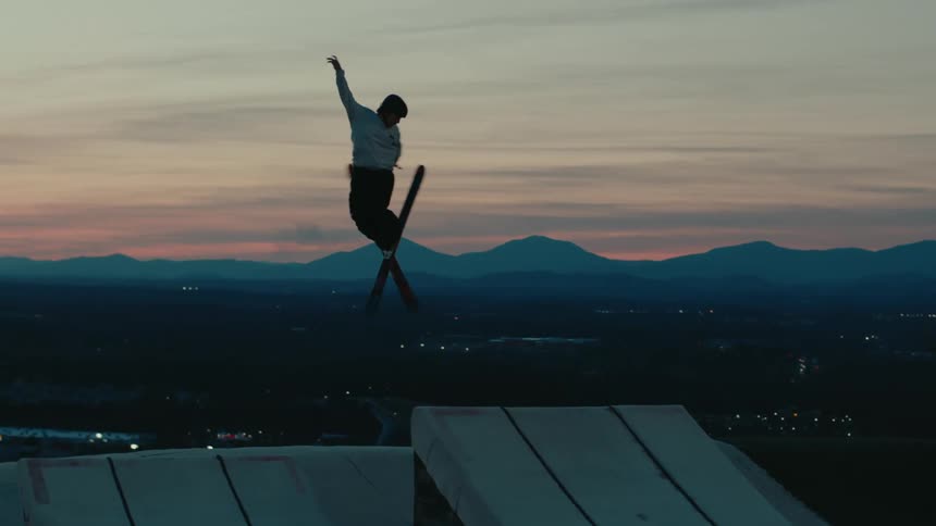 Man snow skiing at dusk jumping from a slope