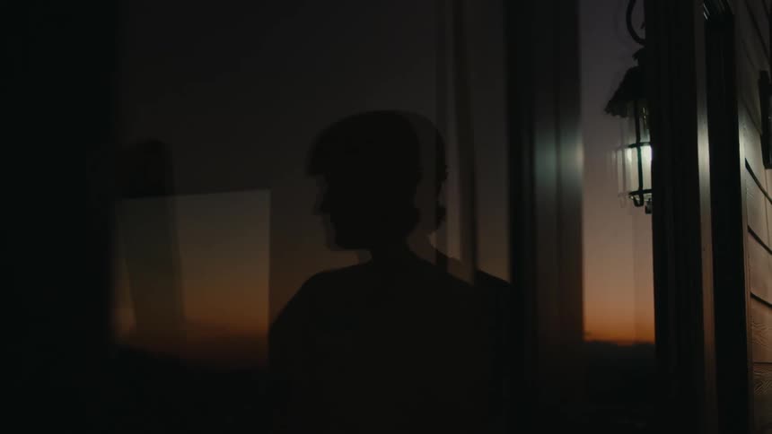 A silhouette of a person in the reflection of a glass window
