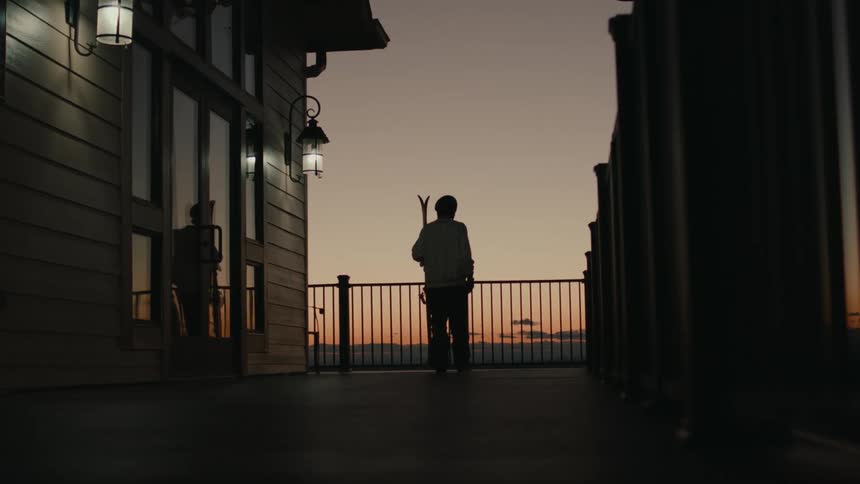 A man carries skis by the lodge