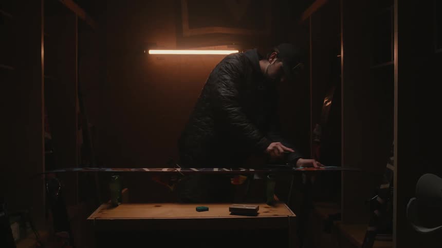 Man using an iron on a snowboard inside a dark room
