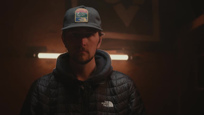 Man in jacket and hat in an indoor environment with low lighting