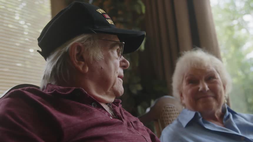 Man putting on a hat while sitting next to a woman