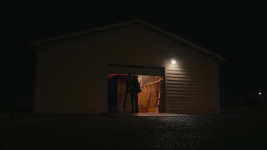 Man opening the door of a shed with snow skiing equipment