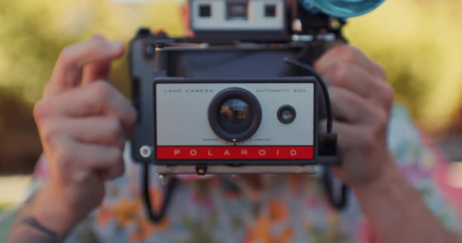 A person with a retro camera takes a photo with a flash on a clear day